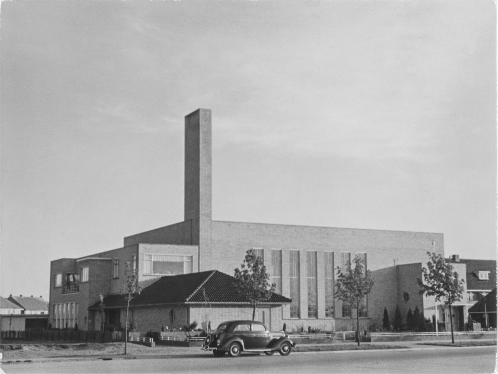Industriegebäude der Neuen Sachlichkeit mit hohem Turm, davor ein Automobil der 1930er Jahre — Fotografie von Elisabeth Hase